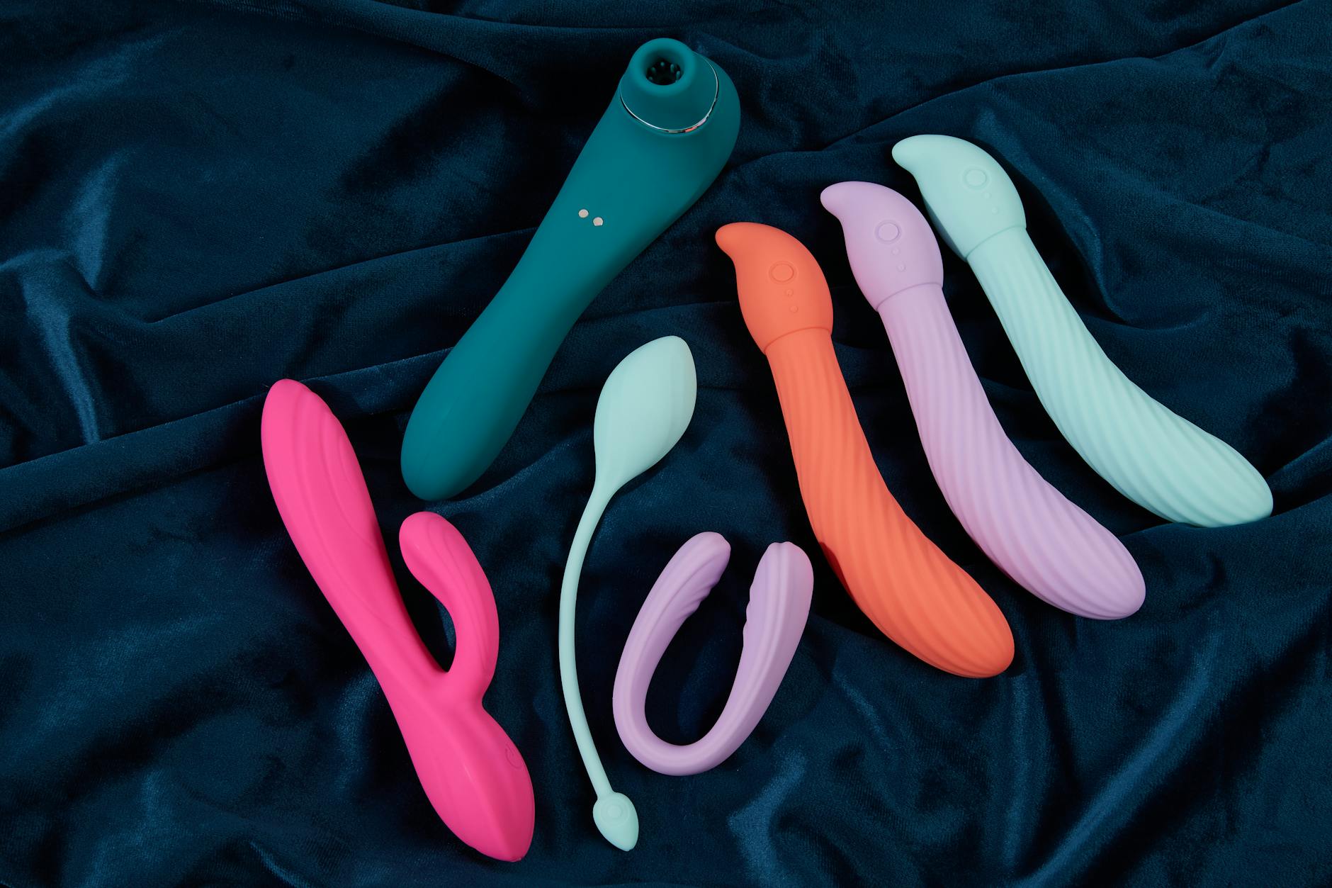 A close-up of a hand holding an orange vibrator against a minimalistic purple backdrop, showcasing modern sensuality.