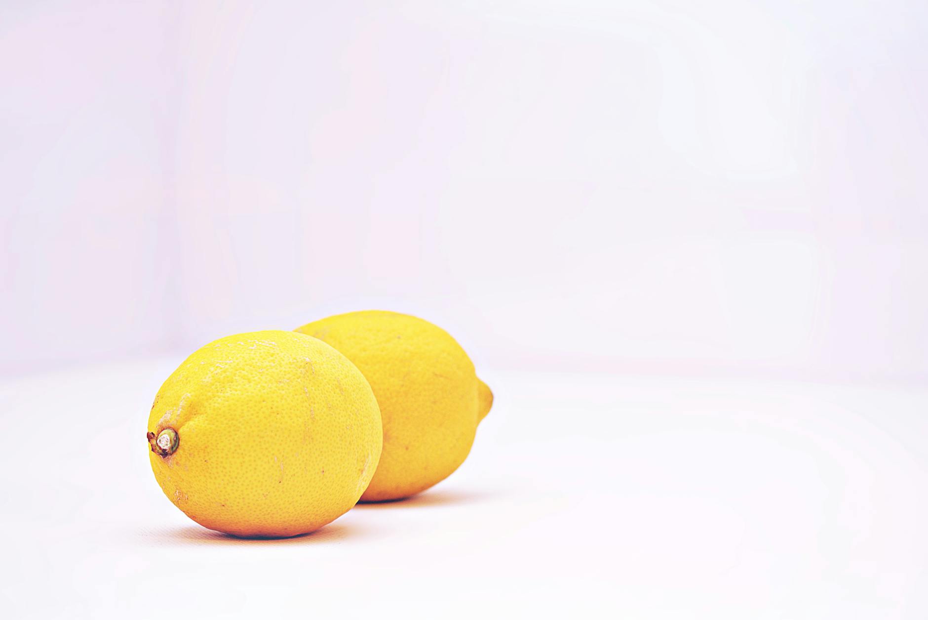Two vibrant lemons placed against a minimalistic white background, symbolizing fresh approaches to pleasure during hormonal change.