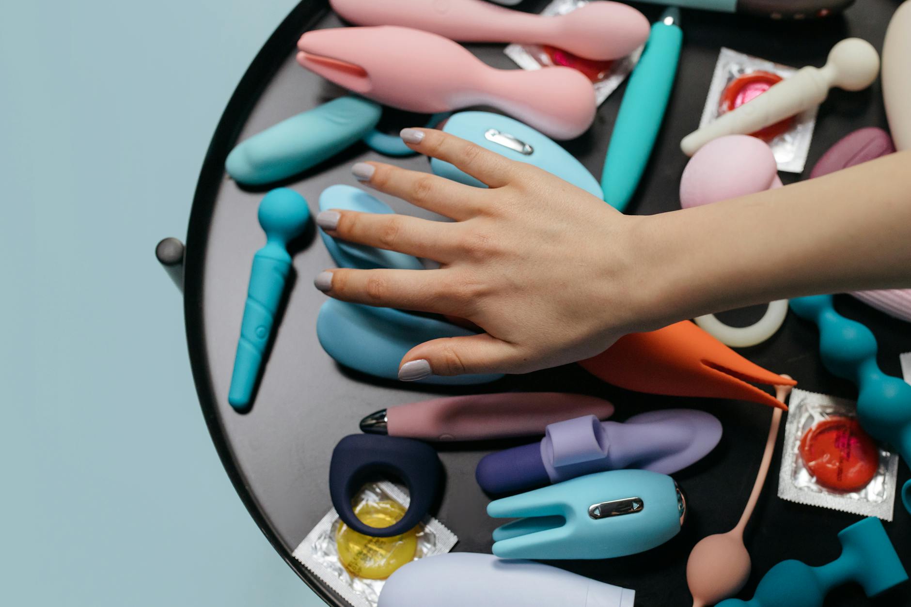 A woman holding contemplative look with colorful vibrators, representing patience during pleasure recovery.