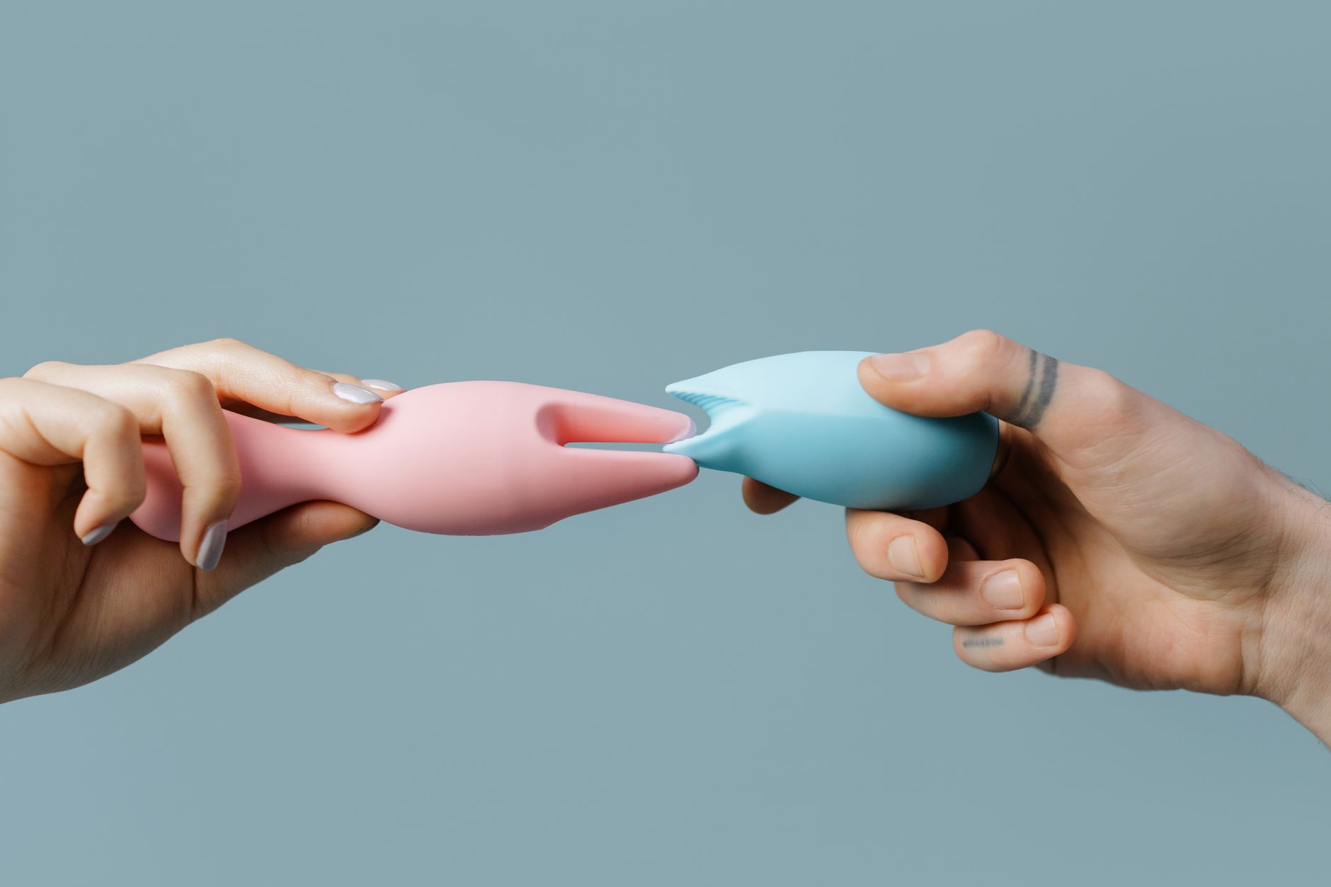 Hands holding colorful silicone clitoral vibrators and lemon suction toys