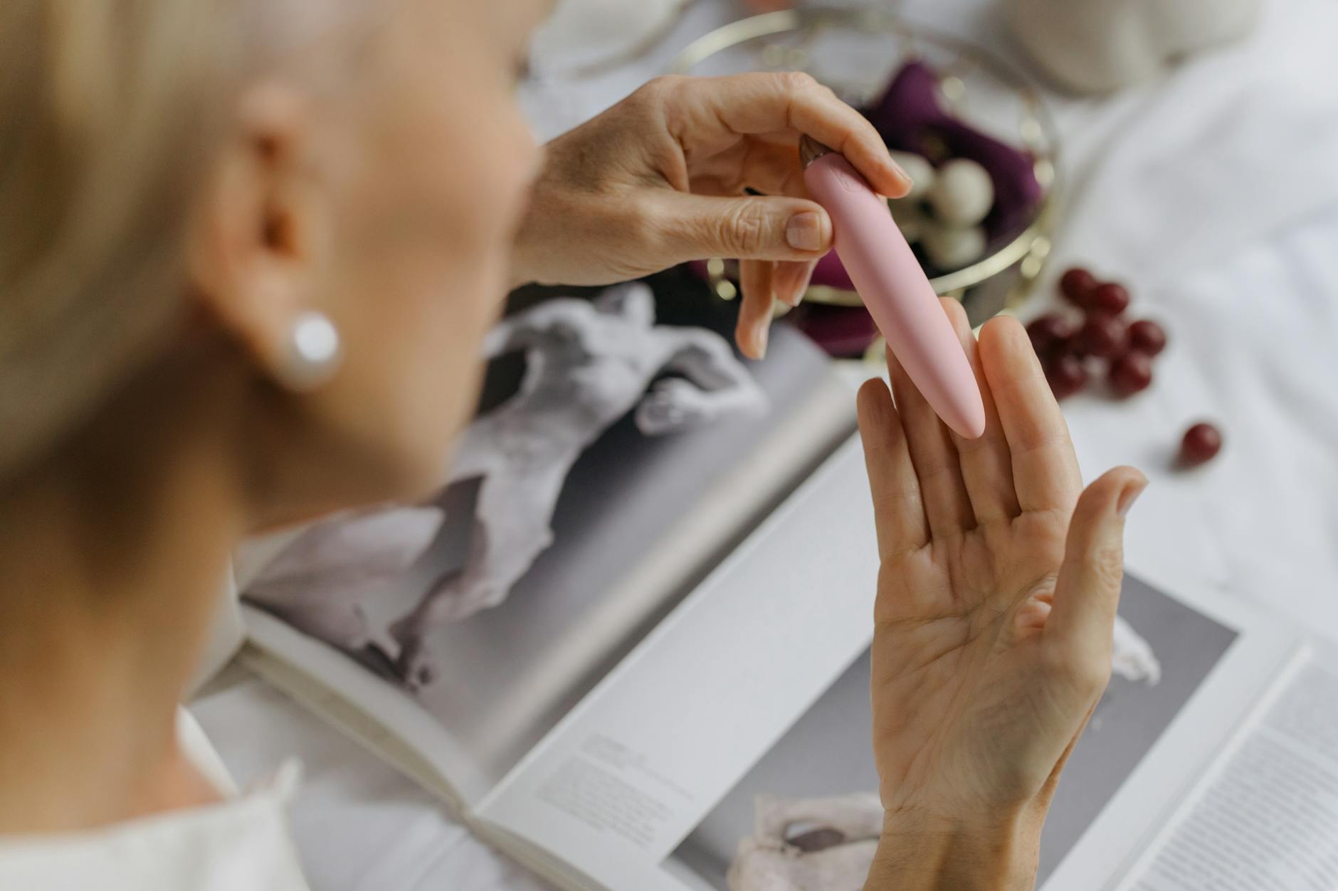 Woman holding vibrators in contemplative pose with eyeglasses, representing intentional pleasure exploration.