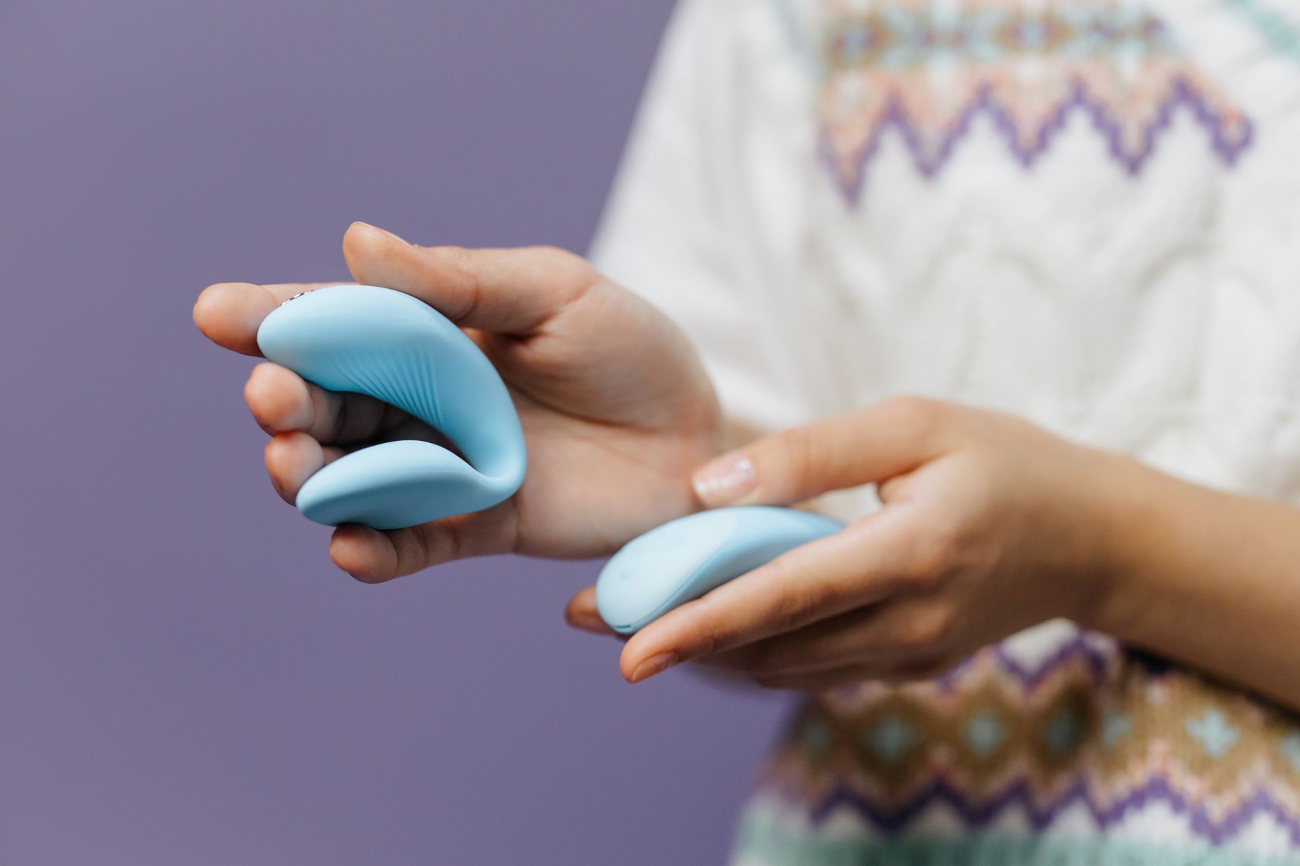 Hands holding a sleek lemon vibrator against a soft background.