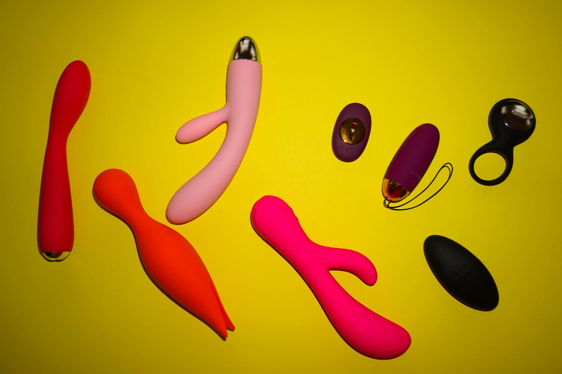Vibrant collection of sex toys including lemon clitoral vibrators arranged on a bright yellow surface