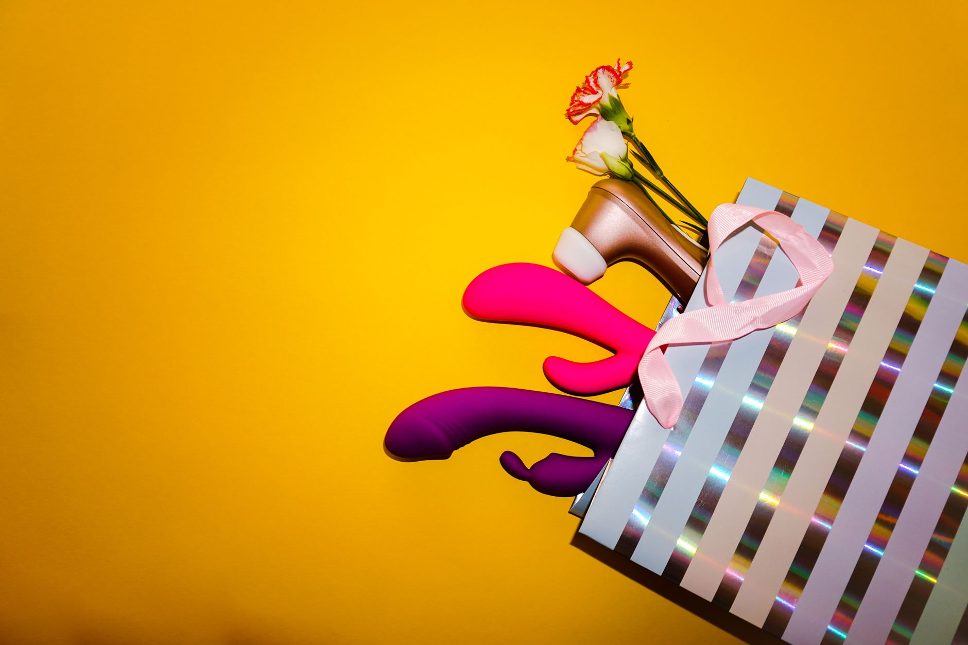 Hand reaching toward a variety of colorful clitoral vibrators displayed on a table