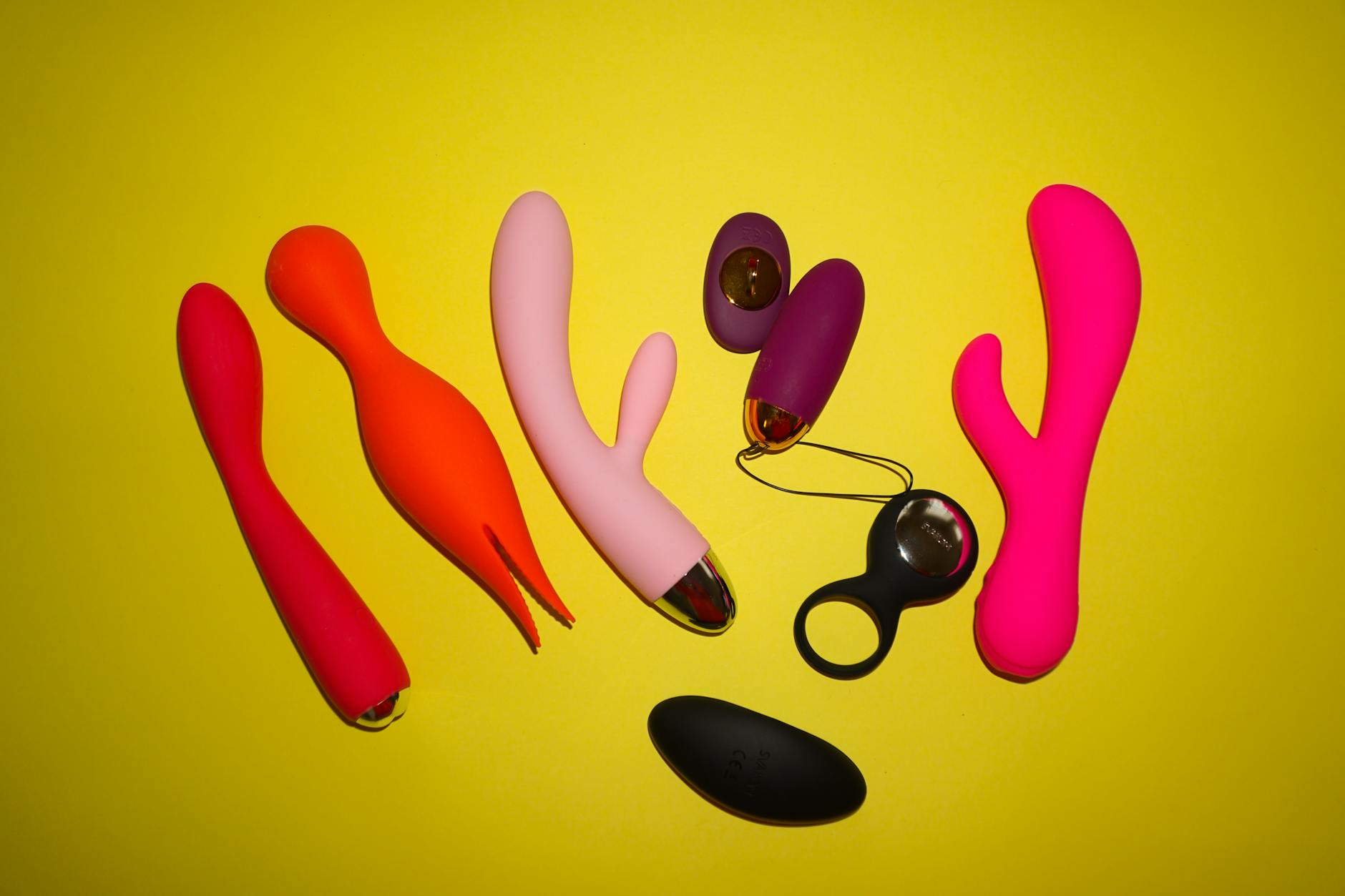 Colorful clitoral vibrators displayed on bright yellow background showcasing various shapes designed for efficient pleasure